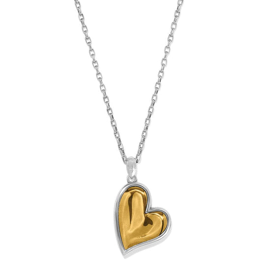 The Cascade Heart Reversible Gold and Silver Necklace with the gold side showing the heart-shaped pendant hanging on a twisted chain. The background is plain and white.