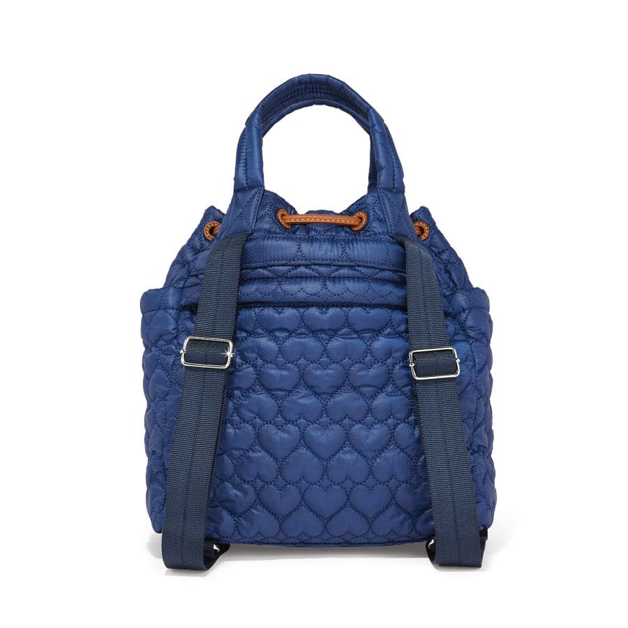 Back view of a blue quilted Kenny Convertible Backpack with adjustable shoulder straps and tan accents hangs against a white background, surrounded by metal zippers and buckles.