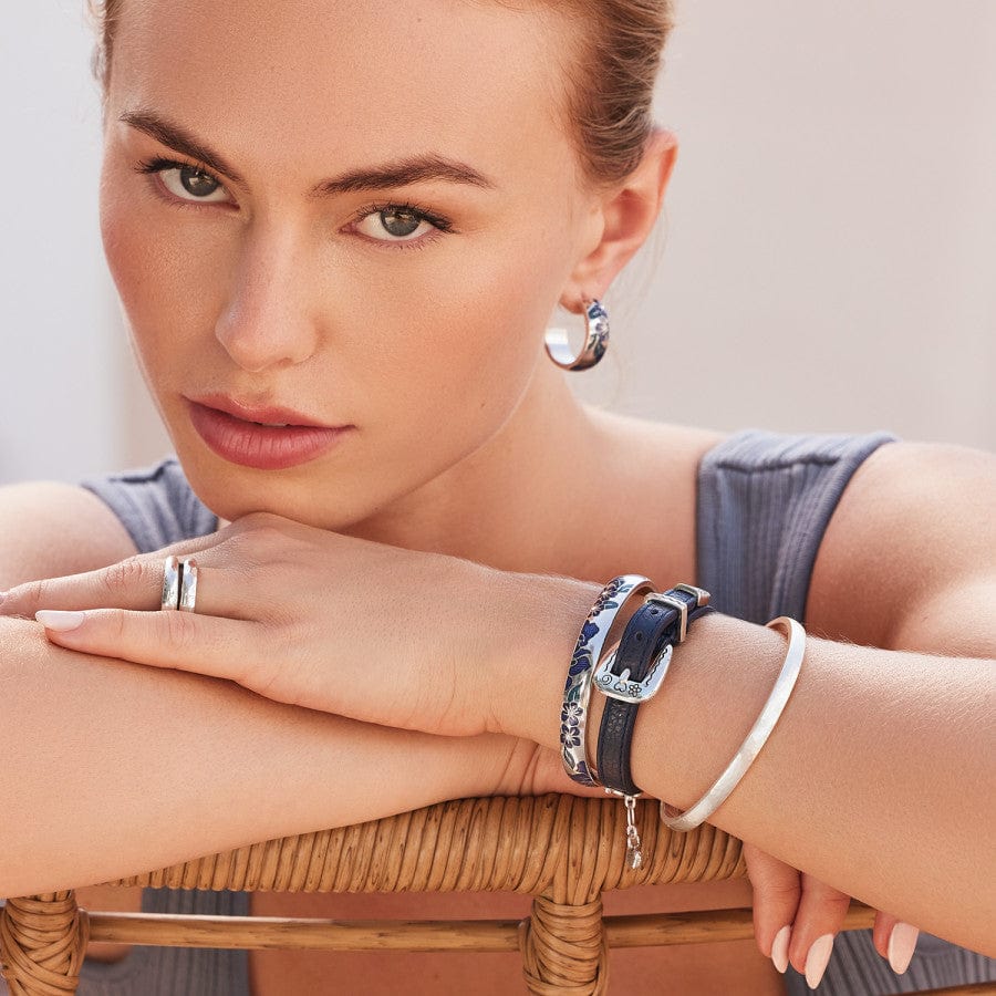 Terra Hoop Earrings worn by a model, posing with her chin resting on her crossed hands adorned with jewelry, looking directly at the camera, against a neutral background.