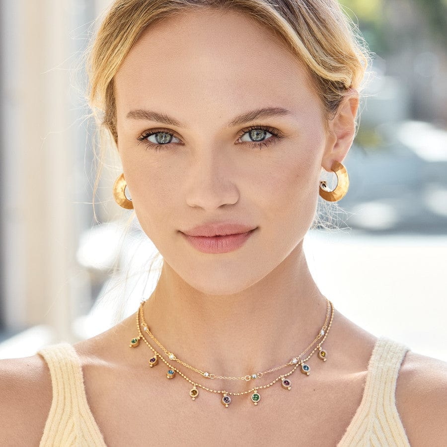 model on beach wearing the Twinkle Mod Droplet Reversible Necklace with gold earrings