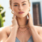 Model wearing Twinkle Mod Droplet Reversible Necklace in gold with matching ring and earrings