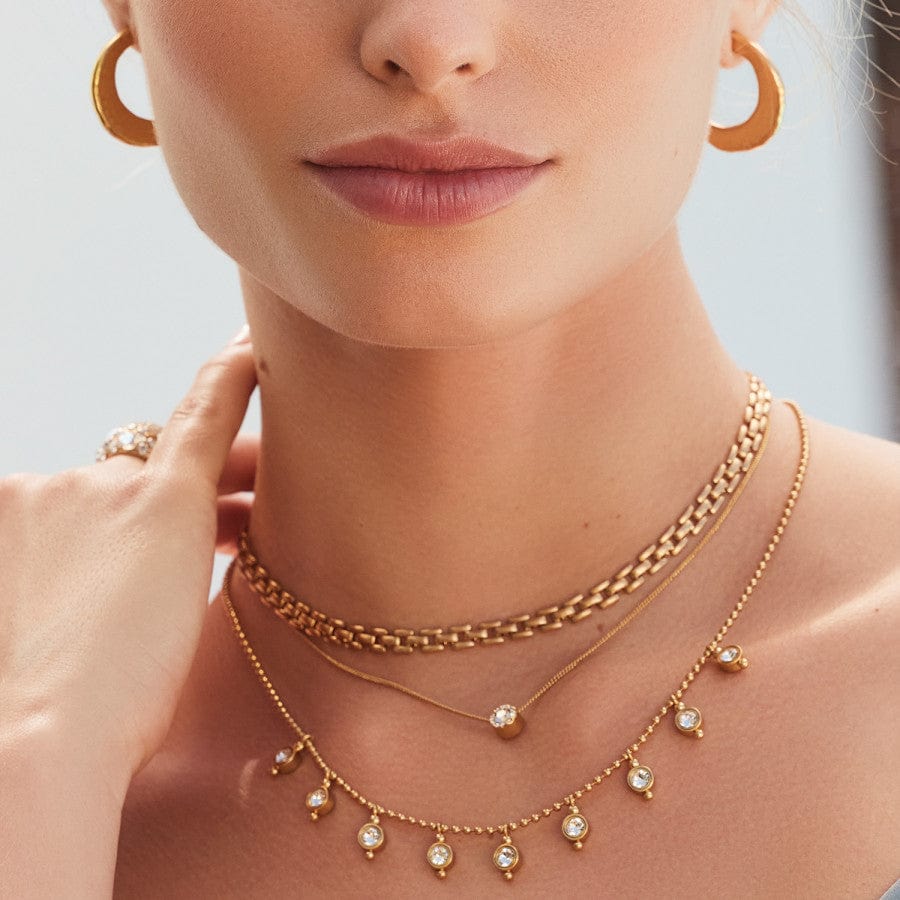 Close up of model wearing Twinkle Mod Droplet Reversible Necklace in gold with matching ring and earrings