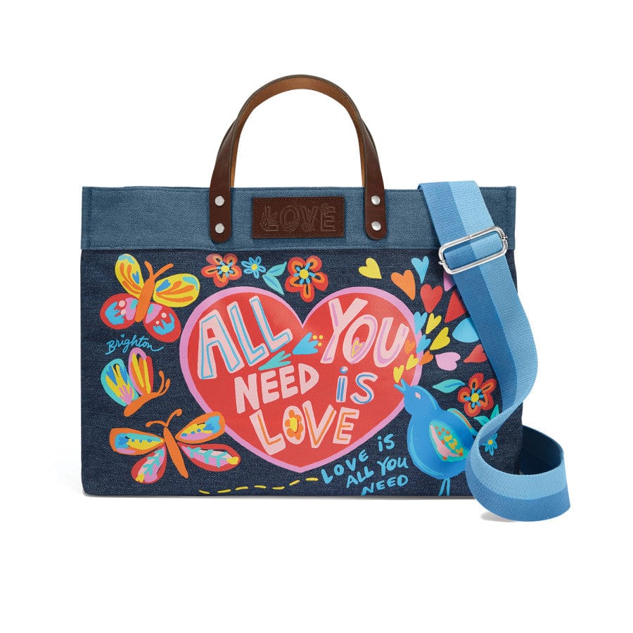 A colorful denim bag All You Need East West Denim Tote features the text "ALL YOU NEED IS LOVE," adorned with butterflies, flowers, and a bird. It has brown leather handles and a blue shoulder strap.