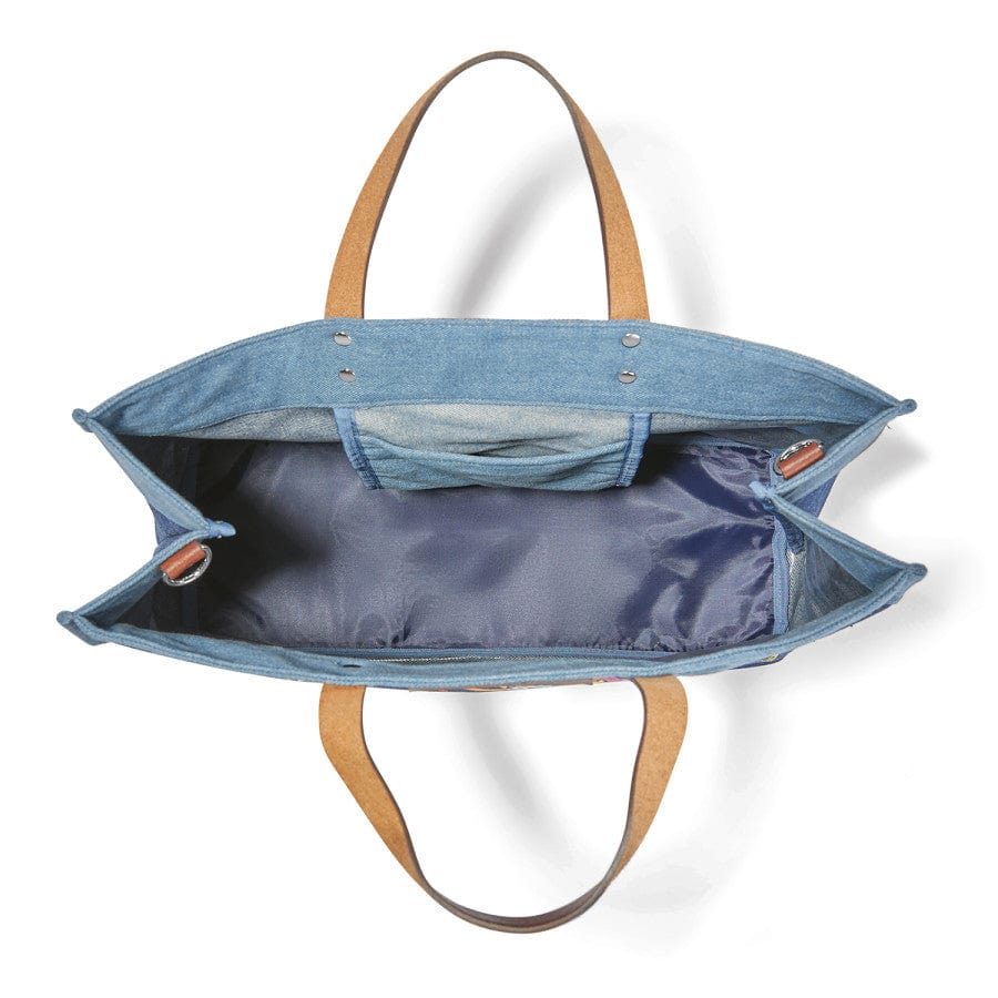 Inside view of a light blue All You Need East West Denim Tote bag with tan handles, open to reveal a dark blue interior, two side pockets, and a central section, against a white background.