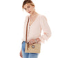 Model wearing Contempo Straw Pouch purse in natural-luggage in peach top and blue jeans, looking at camera