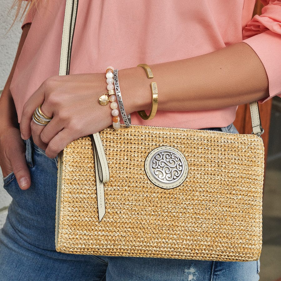 Close up of model wearing Contempo Straw Pouch purse in natural-white in peach top and blue jeans with complementary bracelets & ring 